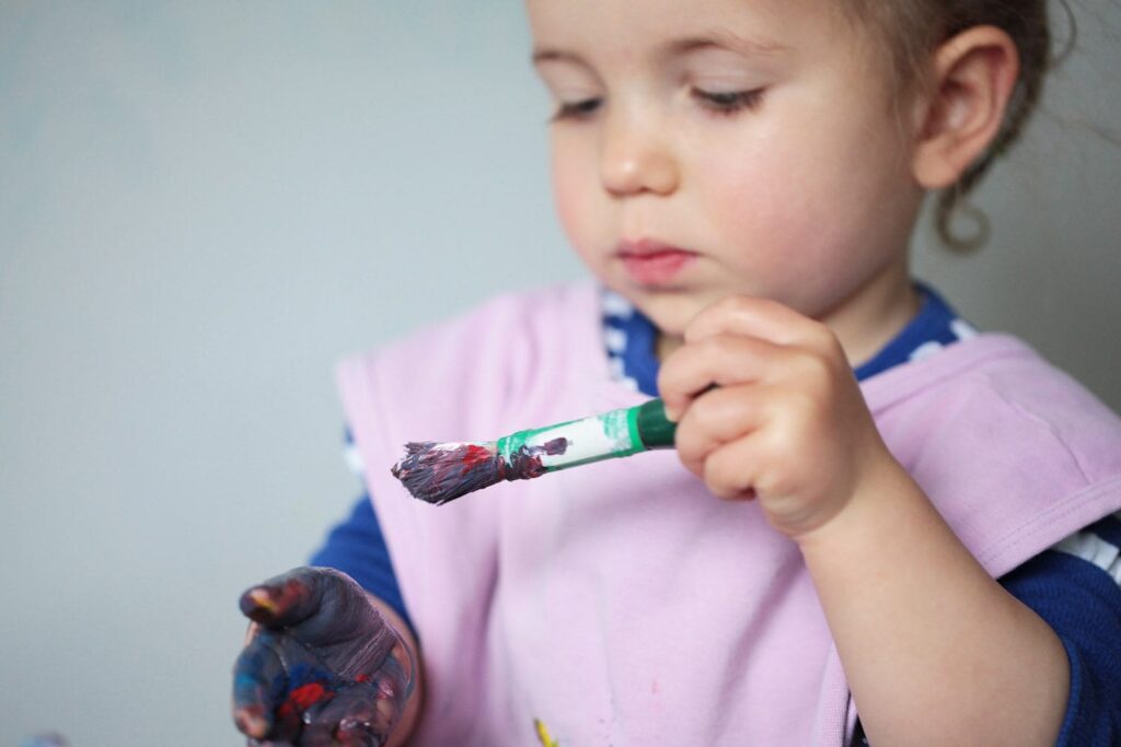 painting hand image of toddler with brush